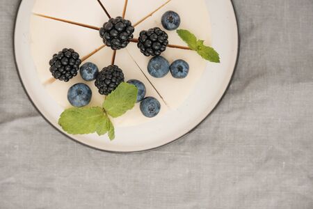 delicious creamy cheesecake with blueberries and blackberries. view from above. grey background. minimalismの写真素材