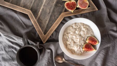 porridge with figs on coconut milk on a gray background and a wooden stand. Ingredients for a healthy breakfast. Clean food, vegan food concept. View from aboveの写真素材