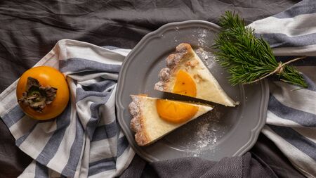 cheesecake and persimmons, dark gray background. rustic breakfast concept. top viewの写真素材
