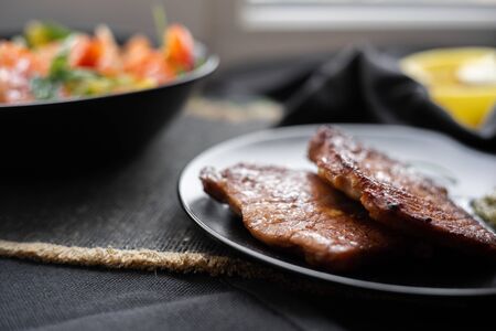 fried beef steaks with vegetable salad. Top view. Healthy food. Diet. Dark background. Daylightの写真素材