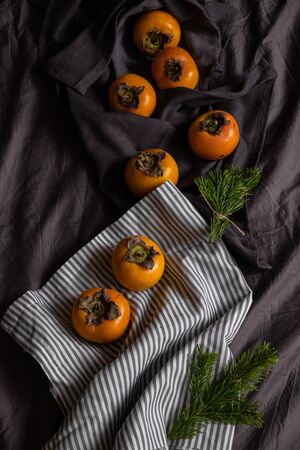Ripe orange persimmon fruit on a dark gray background. Vegetables. Vegetarianismの写真素材