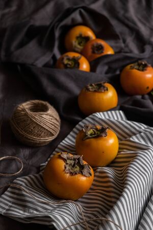 Ripe yellow persimmon with Christmas tree branches on a dark background. New Year's still life. top viewの写真素材