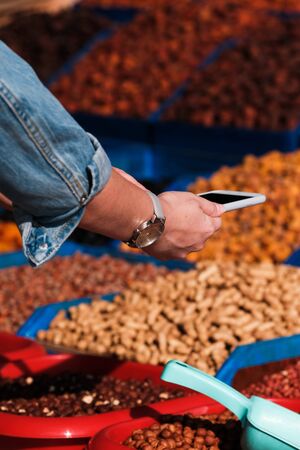 dried fruits and nuts on the counter. A man photographs dried fruits on the phone. daylightの写真素材