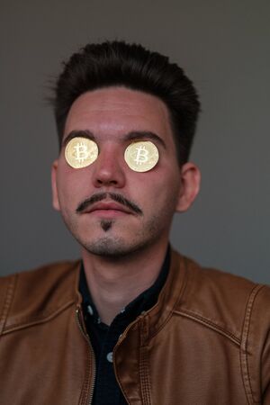 young man with bitcoins in the eye sockets on a dark background. financier. business meeting. mafiaの写真素材