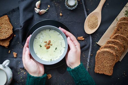 female hands in a sweater hold a plate with soup in their hands. Winter food concept. Home comfort.の写真素材