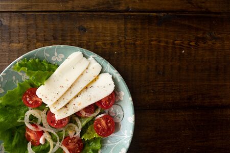 lettuce, tomatoes, onions, cheese and olive oil. Vegetable plateau. Wood background