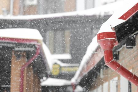 Winter background - snowy winter houses and drainpipes in defocus. Snowfall in the cityの写真素材