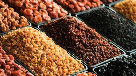 A pile of raisins, dried apricots of various types of dried fruits and other organic products on the counter of the store.の写真素材