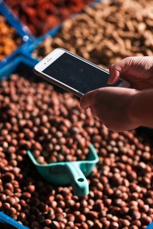 dried fruits and nuts on the counter. A man photographs dried fruits on the phone. daylightの写真素材