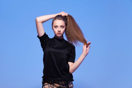 Attractive hipster girl on color background. Portrait of gorgeous female model posing in fashion color clothes in studio. The concept of stylish and perfect skin and body. trending neon background.の写真素材