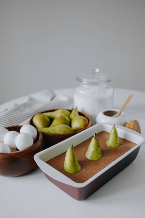 Cooking pear cake for Easter. Ingredients for making dough. Chocolate cake with pears in rustic style closeup. Easter celebration. Easter tableの写真素材