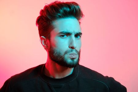 Beautiful caucasian young man portrait isolated on multicolored neon light backgroud. Young, smiling, surprised, screaming. Human emotions, facial expression concept. Trendy colors.Advertising conceptの写真素材