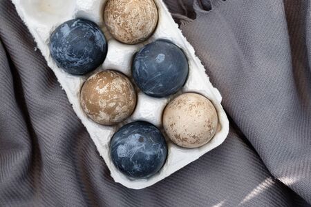 Naturally dyed eggs prepared for Easter on gray texture tablecloth background. Happy Easter card....