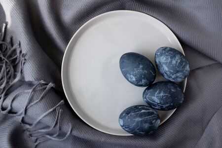 Naturally dyed blue eggs prepared for Easter on gray texture tablecloth background. Happy Easter card. Top view. Easter background with Easter eggs in a ceramic gray bowl. Background with easter eggs.の写真素材