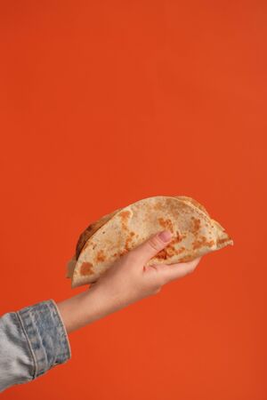 National food concept. Mexican national food tacos or Tatar national food - kystyby in hand on an orange background. Food in a tortilla.の写真素材