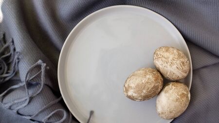 Naturally dyed eggs prepared for Easter on gray texture tablecloth background. Happy Easter. Easter background with Easter eggs in a ceramic gray bowl. Background with easter eggs.の写真素材