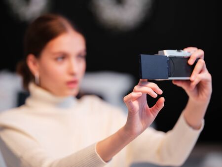 Cute millennial woman or girl makes selfie on mirrorless camera to share on internet social media...