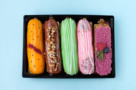 Close-up multi-colored eclairs with different taste. View from above. Breakfast concept. Modern...