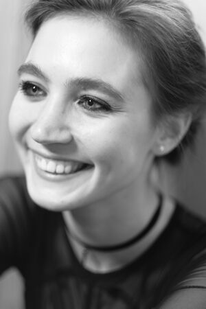 Girl poses for the photographer. Black-white portrait of a beautiful young girl in a black dress and a striped shirt with a choker on her neck. Girl poses for the photographerの写真素材