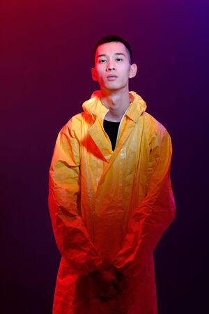 Asian man in a yellow suit of chemical protection on a colored trendy background. Fashion shooting...