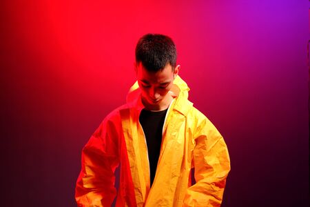 Asian man in a yellow suit of chemical protection on a colored trendy background. Fashion shooting...