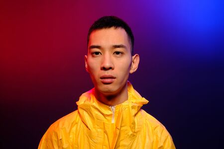 Asian man in a yellow suit of chemical protection on a colored trendy background. Fashion shooting...
