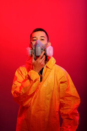 Asian man in a yellow suit of chemical protection and in a protective mask on a colored trendy background.の写真素材
