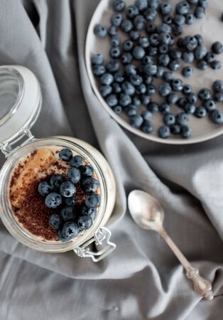 Delicious dessert: tiramisu in a glass jar and natural yogurt in a glass cup with fresh berries, strawberries and blueberries. Rustic breakfast in the kitchen. Kinfolk style lifeの写真素材