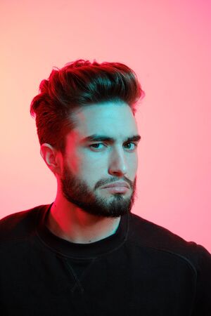 Beautiful caucasian young man portrait isolated on multicolored neon light backgroud. Young, smiling, surprised, screaming. Human emotions, facial expression concept. Trendy colors.Advertising conceptの写真素材