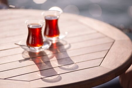 A pair of glass cups with black tea on a wooden table in the open air. Tea terrace. Tea ceremony.の写真素材