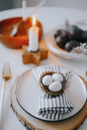Rustic easter table setting with eggs. Easter table setting with white plate, gray textile napkin,...