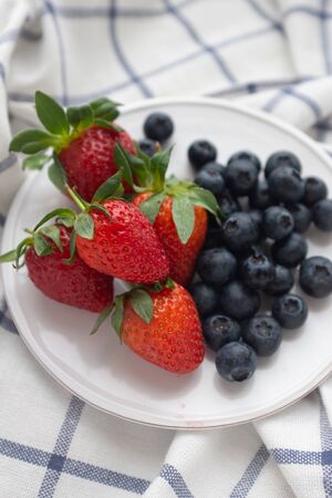 Beautiful healthy breakfast plate with strawberries and blueberries on a checkered napkin on the tableの写真素材