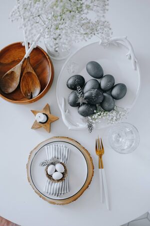 Rustic easter table setting with eggs. Easter table setting with white plate, gray textile napkin, quail and chicken eggs and blossom branch on table. Top view, flatlayの写真素材