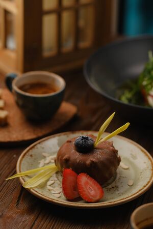 Chocolate dessert beautifully decorated with strawberries lies on a dessert plate. Serving dessert in a cafe.の写真素材