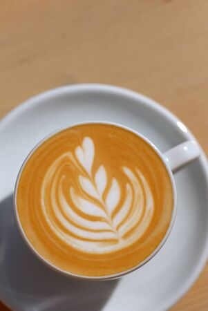 Beautiful blue mug with cappuccino or latte coffee on a wooden table. View from above. Breakfast in the cafe.の写真素材