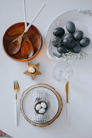 Rustic easter table setting with eggs. Easter table setting with white plate, gray textile napkin, quail and chicken eggs and blossom branch on table. Top view, flatlayの写真素材
