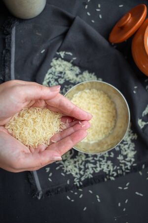 A scattering of rice, a handful of rice, rice in a metal bowl on a dark background. Healthy eating conceptの写真素材