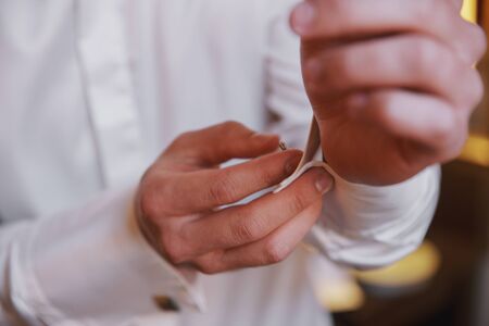 Grooms morning preparation.Handsome man getting dressed and preparing for the wedding.Friend helping groom getting ready in the room for wed day.の写真素材