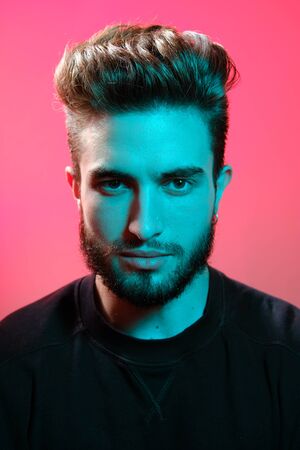 Beautiful caucasian young man portrait isolated on multicolored neon light backgroud. Young, smiling, surprised, screaming. Human emotions, facial expression concept. Trendy colors.Advertising conceptの写真素材