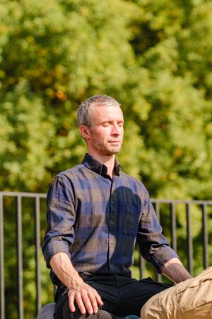 A young man meditates outdoors in a park. Meditation and yoga, healthy lifestyle concept. Spiritual Restorationの写真素材