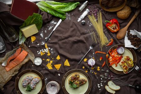 Traditional italian food on a dark background, flat lay. Various ingredients for italian food. Bruschetta, pasta, tomatoes, peppers, cheese, etc.の写真素材