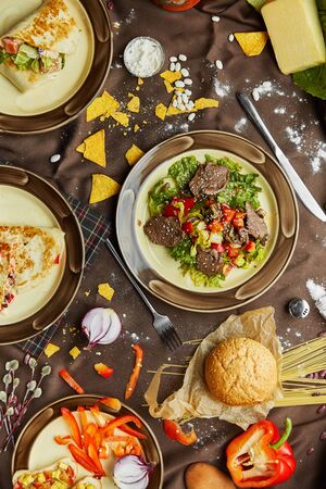 Beef steak salad with cherry tomatoes, cucumbers, red onions, romaine salad and lime mustard olive oil salad dressing on dark background, top viewの写真素材