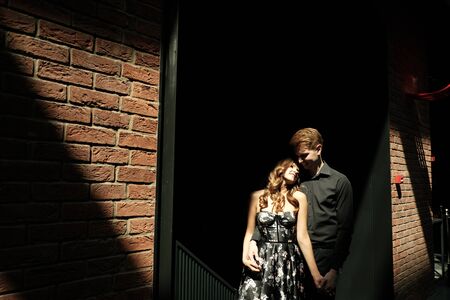Young beautiful couple - a girl in a magnificent dress and a guy in a black shirt and trousers are in a building with a beautiful interior and high glass ceilings. Concept of romance and loveの写真素材
