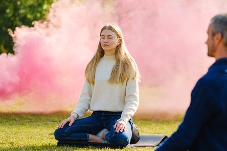 yoga exercise in the park. woman practices yoga and meditates in the lotus position in the parkの写真素材