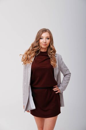 Studio portrait of casual blonde girl in coat on plain background. Office style in clothesの写真素材