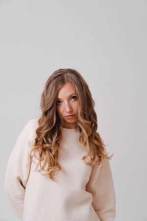 Studio portrait of young blonde stretching arms on plain backgroundの写真素材