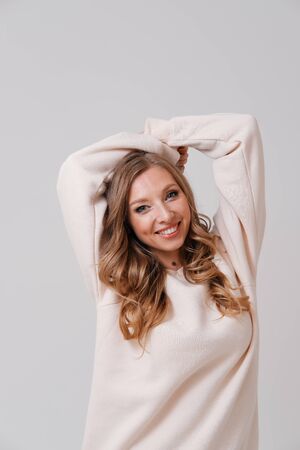Studio portrait of young blonde stretching arms on plain backgroundの写真素材