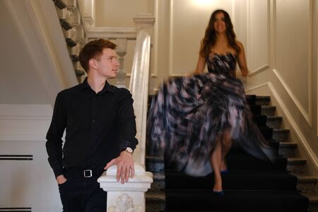 Young beautiful couple - a girl in a magnificent dress and a guy in a black shirt and pants stand or...