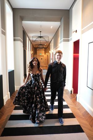 Young beautiful couple - a girl in a magnificent dress and a guy in a black shirt and trousers are in a building with a beautiful interior and high glass ceilings. Concept of romance and loveの写真素材