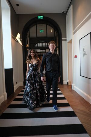 Young beautiful couple - a girl in a magnificent dress and a guy in a black shirt and trousers are in a building with a beautiful interior and high glass ceilings. Concept of romance and loveの写真素材